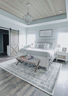 a bedroom with a large bed and white furniture in the room, along with an area rug on the floor