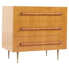 a wooden dresser with three drawers and two bamboo handles on each drawer, against a white background