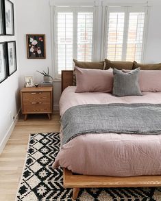 a bed with pink sheets and pillows in a bedroom next to two pictures on the wall