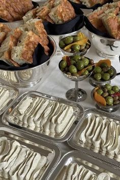 several trays filled with different types of food on top of a white table cloth