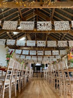 a room filled with lots of wooden chairs and tables covered in white lace hanging from the ceiling