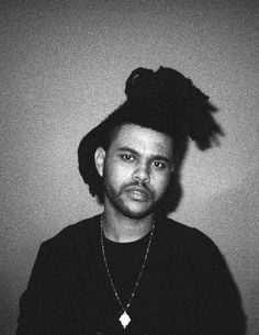 a black and white photo of a man with a feather on his head wearing a necklace