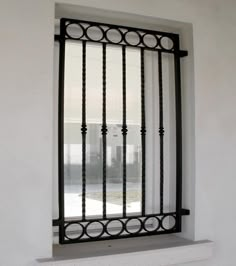 a window with iron bars on it and a white wall in the backround