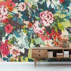 a floral wallpaper with pink, blue and green flowers on the sideboard next to a bookcase