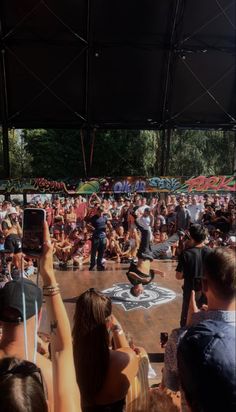 a group of people standing on top of a stage with one person holding up a cell phone