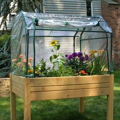 a wooden planter filled with lots of flowers on top of a grass covered field