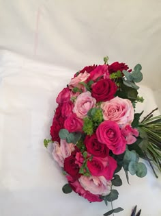 a bouquet of pink and red flowers sitting on top of a white cloth covered table