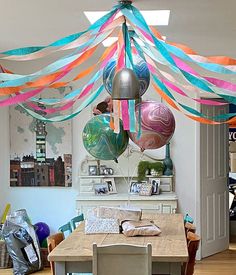 a dining room with balloons and streamers hanging from it's ceiling above the table