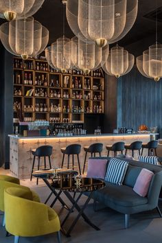 a bar with chairs, tables and lights hanging from the ceiling