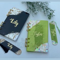 three personalized notebooks with name tags on them next to flowers and other items