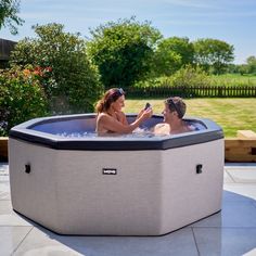 a man and woman sitting in an outdoor hot tub