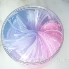 a glass filled with liquid sitting on top of a white counter next to a pink and blue object