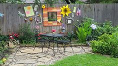 a garden with flowers, plants and pictures on the fenced in area next to it