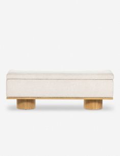 a white bench sitting on top of a wooden table next to a white wall and floor