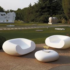 three white chairs sitting in the middle of a park