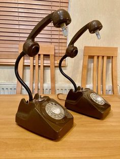 two old fashioned telephones sitting on top of a wooden table next to each other