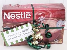 nestle coffee wrapped in green ribbon and tied with gold bow, next to holiday gift box