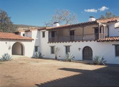 a large white house with red tile roofing and two balconies on the second floor