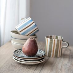 a wooden table topped with plates and cups filled with fruit next to a cup on top of a saucer