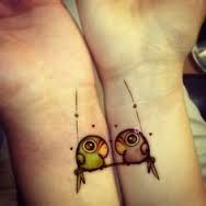 two small birds sitting on top of each other's wrists, with hearts in the background