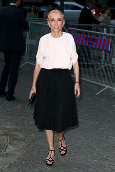 an older woman in a black and white dress is posing for the camera with her hand on her hip