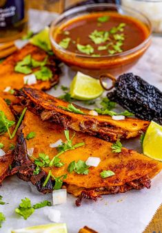 some food that is sitting on top of a table with limes and cilantro