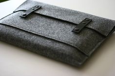 an ipad case is made out of felt and has leather straps on the clasps