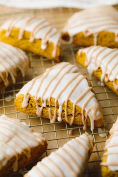 there are many cookies with icing on the cooling rack and one is cut in half