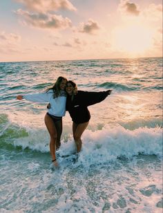 two women are standing in the water at the beach with their arms around each other