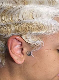 a close up of a person with white hair and piercings on their ears,