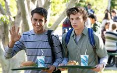 two young men holding plates with sandwiches on them