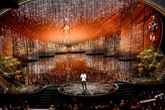 the stage at the oscars is lit up with chandeliers and people standing on it