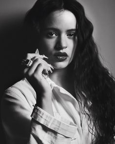 a black and white photo of a woman with long hair holding a ring on her finger