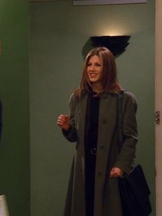 a woman standing in front of a mirror next to another woman wearing a coat and holding a handbag