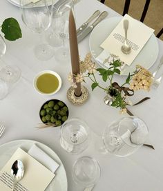 the table is set with wine glasses, silverware and place settings for two people