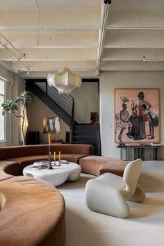 a living room filled with furniture next to a stair case and painting on the wall