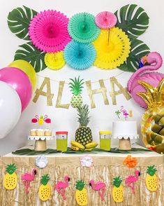 a table topped with pineapples and cupcakes next to a sign that says aloha