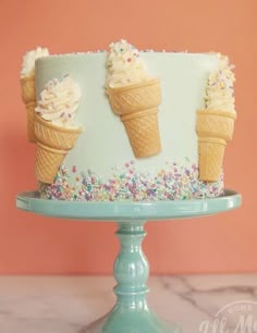 an ice cream cake decorated with sprinkles on a blue pedestal against a pink wall