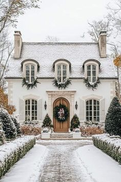 a white house covered in snow with wreaths on the front door and entry way