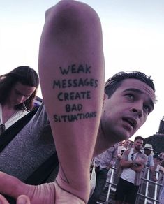 a man with a message tattooed on his arm in front of a group of people