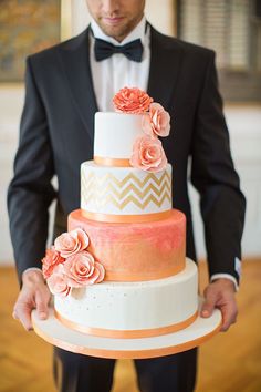 a man in a tuxedo holding a multi - tiered cake