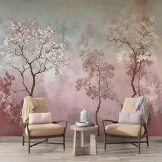 two chairs sitting next to each other in front of a wall with trees painted on it