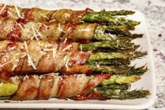 asparagus wrapped in bacon and parmesan cheese on a white platter