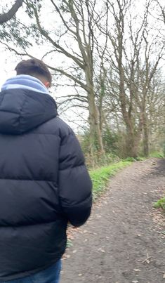 a man is walking down a path in the woods with his back to the camera