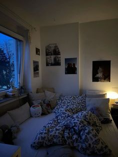 an unmade bed sitting next to a window in a room with pictures on the wall