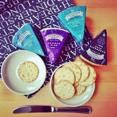 some crackers are sitting on a plate next to a bowl of chips and a fork