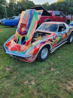 the car is painted with colorful designs on it's hood, and has an engine compartment open