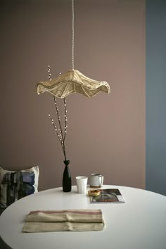 a white table topped with a vase filled with flowers and an umbrella hanging from the ceiling