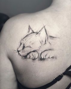 a cat tattoo on the back of a woman's shoulder