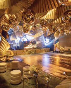 a room filled with lots of shiny balls hanging from the ceiling and chairs around it